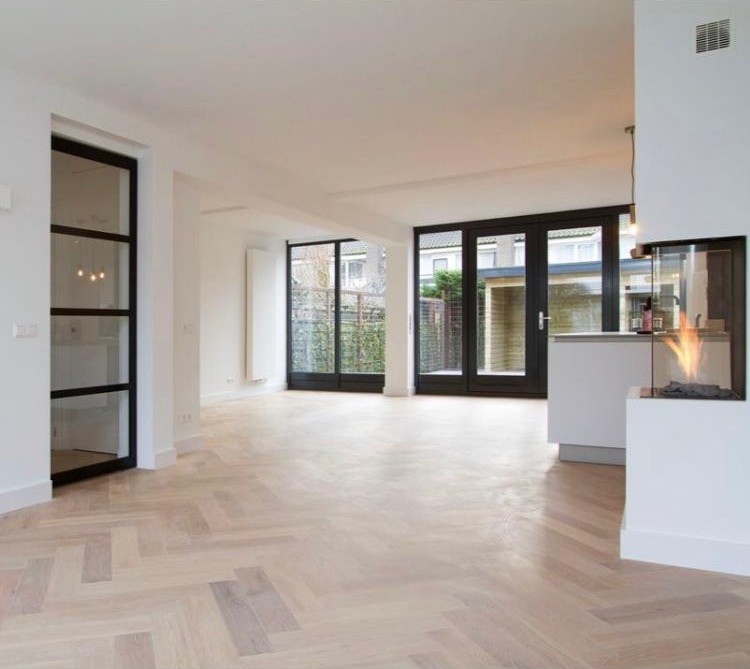 Gerenoveerde woonkamer met visgraatvloer en zwarte kozijnen